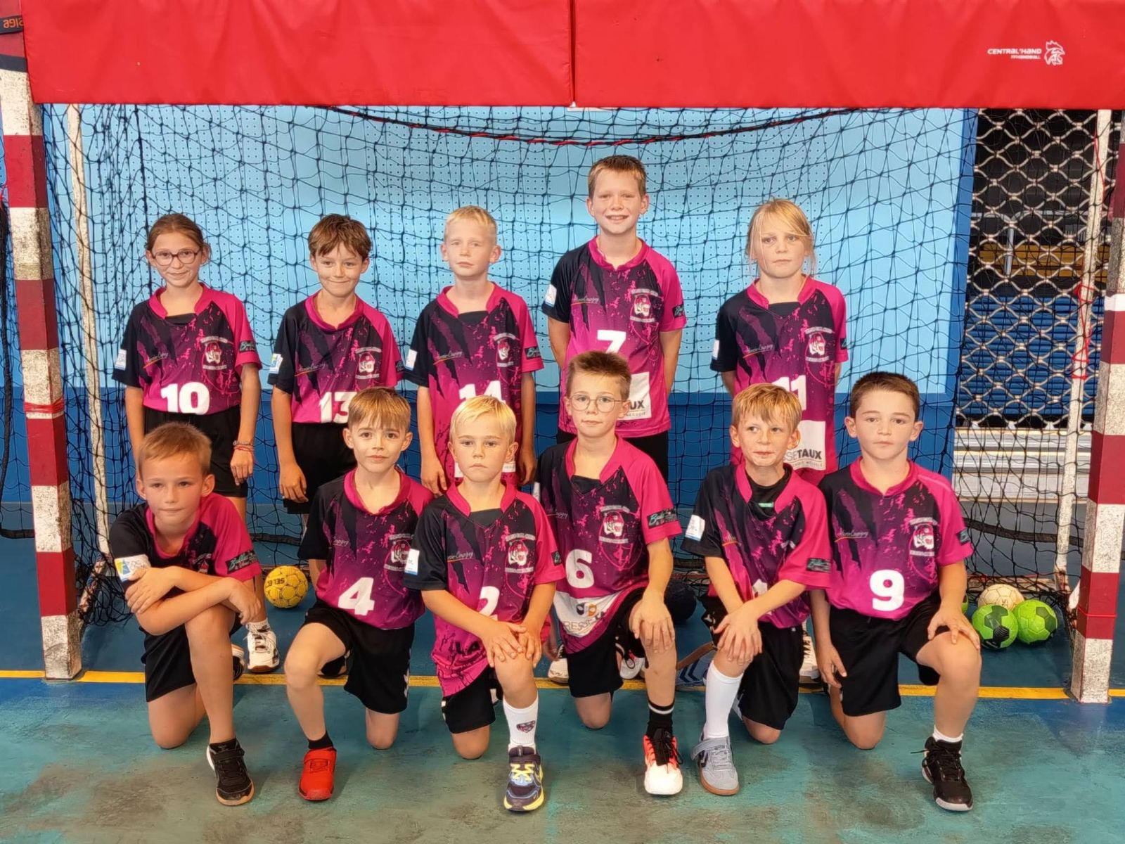Les U11, filles et garçons en maillot rose et noir, posent sur deux rangées devant un but